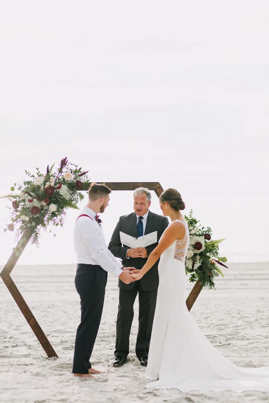 Bride and Groom Vow Exchange | Wooden Hexagon Beach Wedding Ceremony Backdrop with Burgundy Scabiosa, Roses, White Hydrangeas, and Greenery Fall Flower Arrangement Ideas | St Petersburg Photographer Amber McWhorter Photography | Planner Elope Tampa Bay