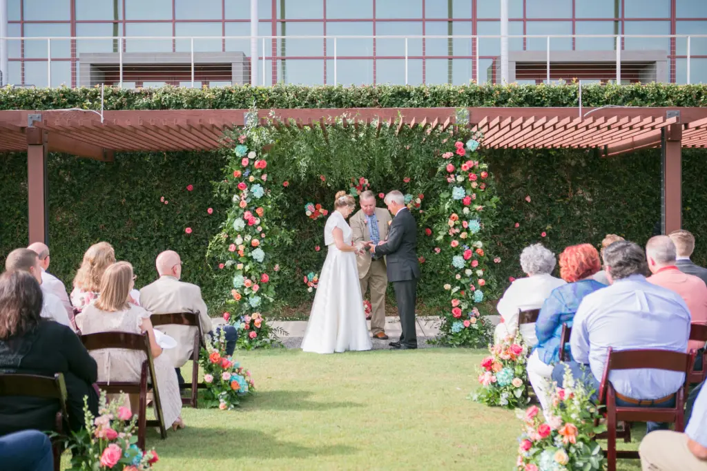 Bride and Groom Exchange Vows in Colorful Turquoise Coral Summer Wedding with Brown Folding Chairs and Floral Inspiration | Tampa Bay Florist Monarch Events and Designs