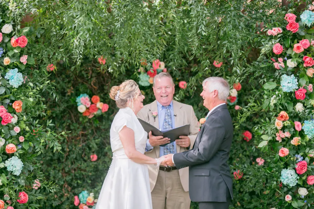 Bride and Groom Exchange Vows in Colorful Turquoise Coral Summer Wedding with Brown Folding Chairs and Floral Inspiration | Tampa Florist Monarch Events and Designs | Tampa Photographer Carrie Wildes Photography
