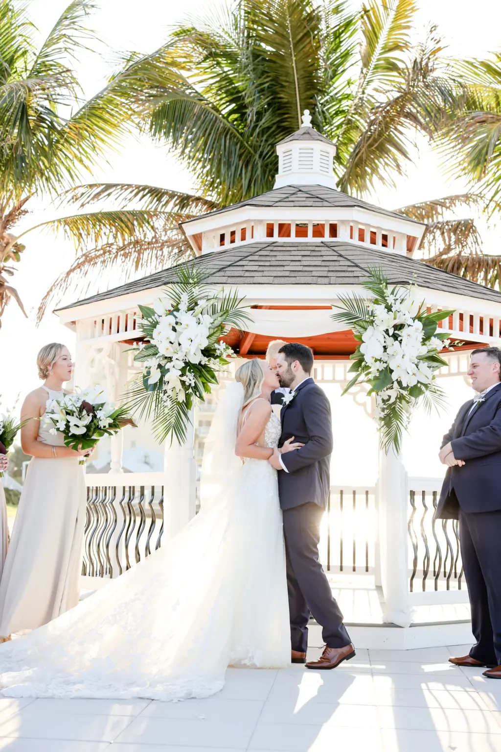 Bride an Groom First Kiss | Tropical Floral Sprays for Gazebo Wedding Ceremony Backdrop with White Orchids, Stock Flowers, and Palm Fronds Ideas | St Pete Videographer Shannon Kelly Films | Photographer Lifelong Photography Studio | Planner Coastal Coordinating | Venue Isla del Sol Yacht Club