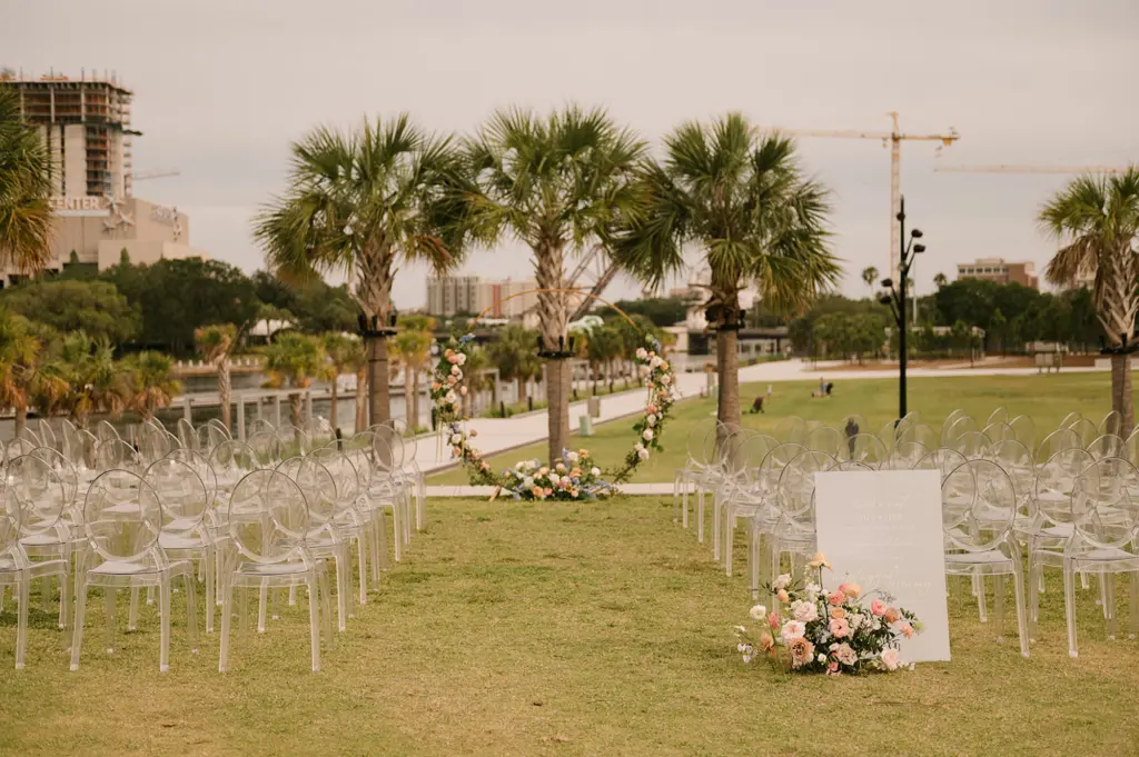 Outdoor Wedding Ceremony with Ghost Chairs from A Chair Affair Rentals | Round Gold Arch with Spring Flower Arrangements | Downtown Event Venue Tampa River Center | Florida Event Planner Coastal Coordinating