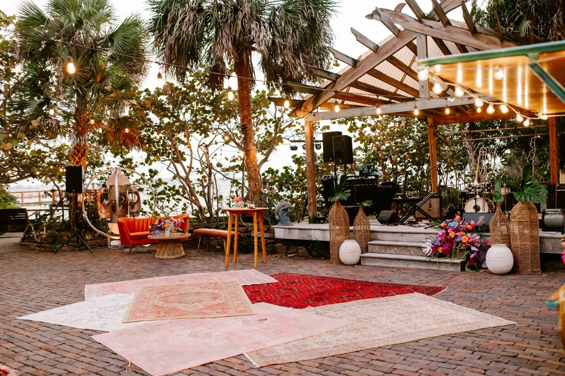 Boho Outdoor Wedding Reception with Red, Orange, and Beige Rugs Decor Ideas | Live Band Stage Inspiration | St Pete Event Planner Wilder Mind Events