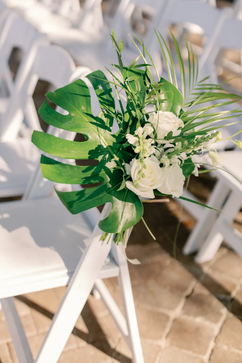 White Floral Monstera Leaf Tropical Wedding Ceremony Decor Ideas on White Folding Chairs