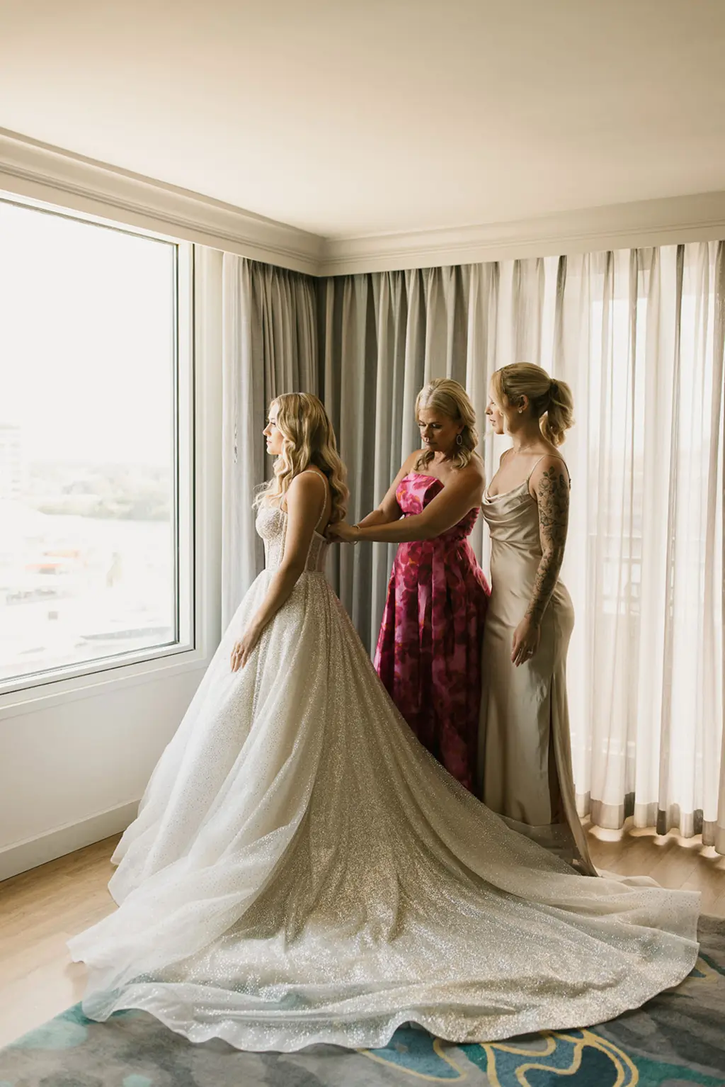 Bride with Sister and Mother Putting on Berta Wedding Dress
