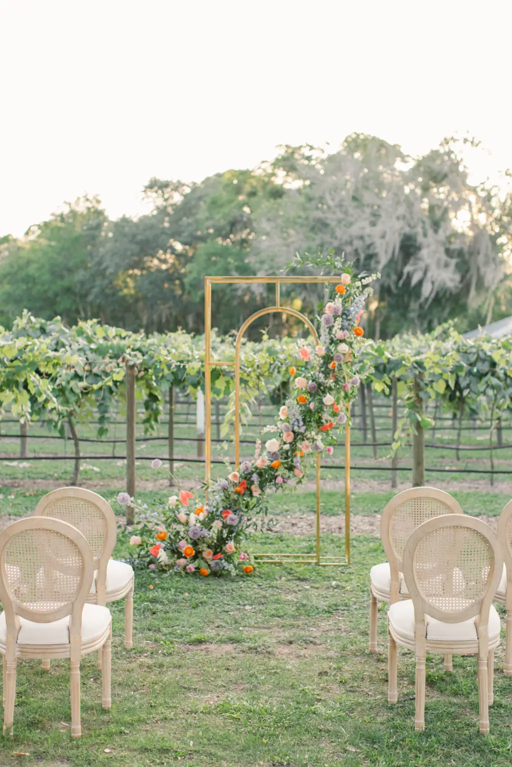 Copper Wedding Ceremony Arch with Whimsical Cascading Pastel Floral Arrangement | Cane Rattan Wedding Chairs | Sarasota Vineyard Wedding Inspiration | Tampa Bay Florist Save The Date Florida | Planner MDP Events | Venue Fiorelli Winery