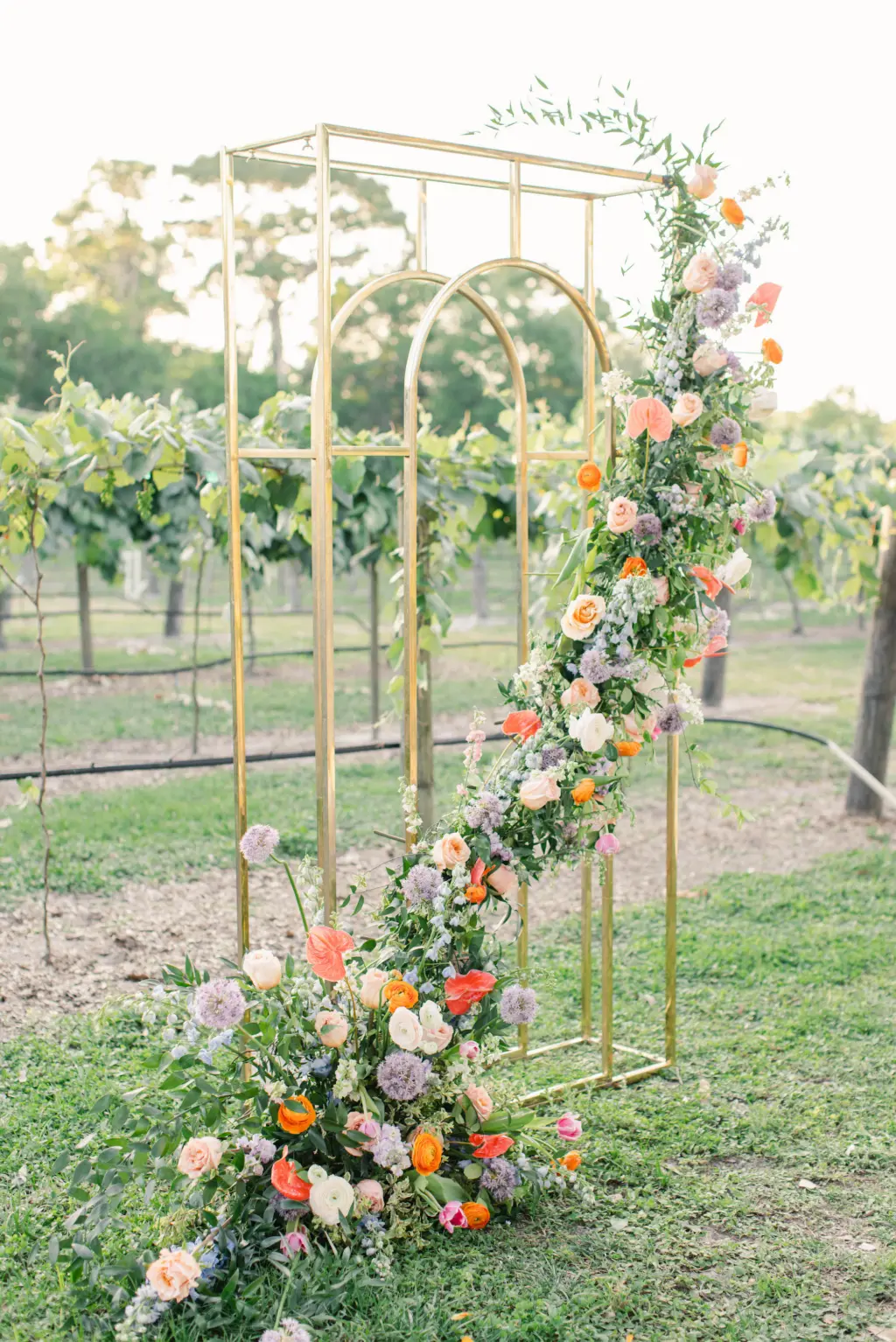 Copper Wedding Ceremony Arch with Whimsical Cascading Pastel Wildflower Floral Arrangement | Cane Rattan Wedding Chairs | Sarasota Vineyard Wedding Inspiration | Tampa Bay Florist Save The Date Florida
