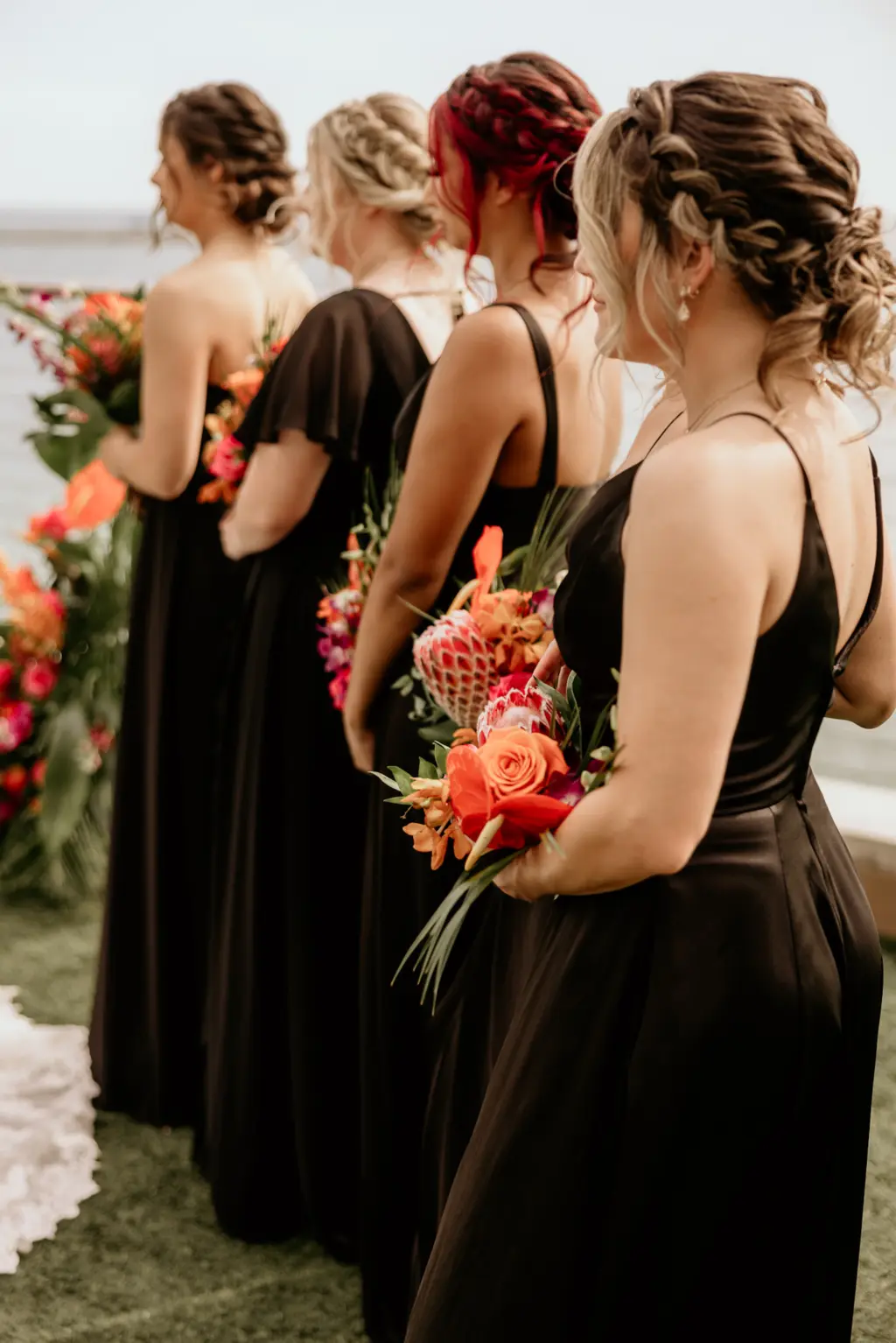 Bridesmaids in all Black Floor Length Mix and Match Wedding Dress Holding Bright Pink, Orange, and Red Tropical Wedding Floral Bouquet Ideas | Clearwater Beach Florist Save the Date Florida