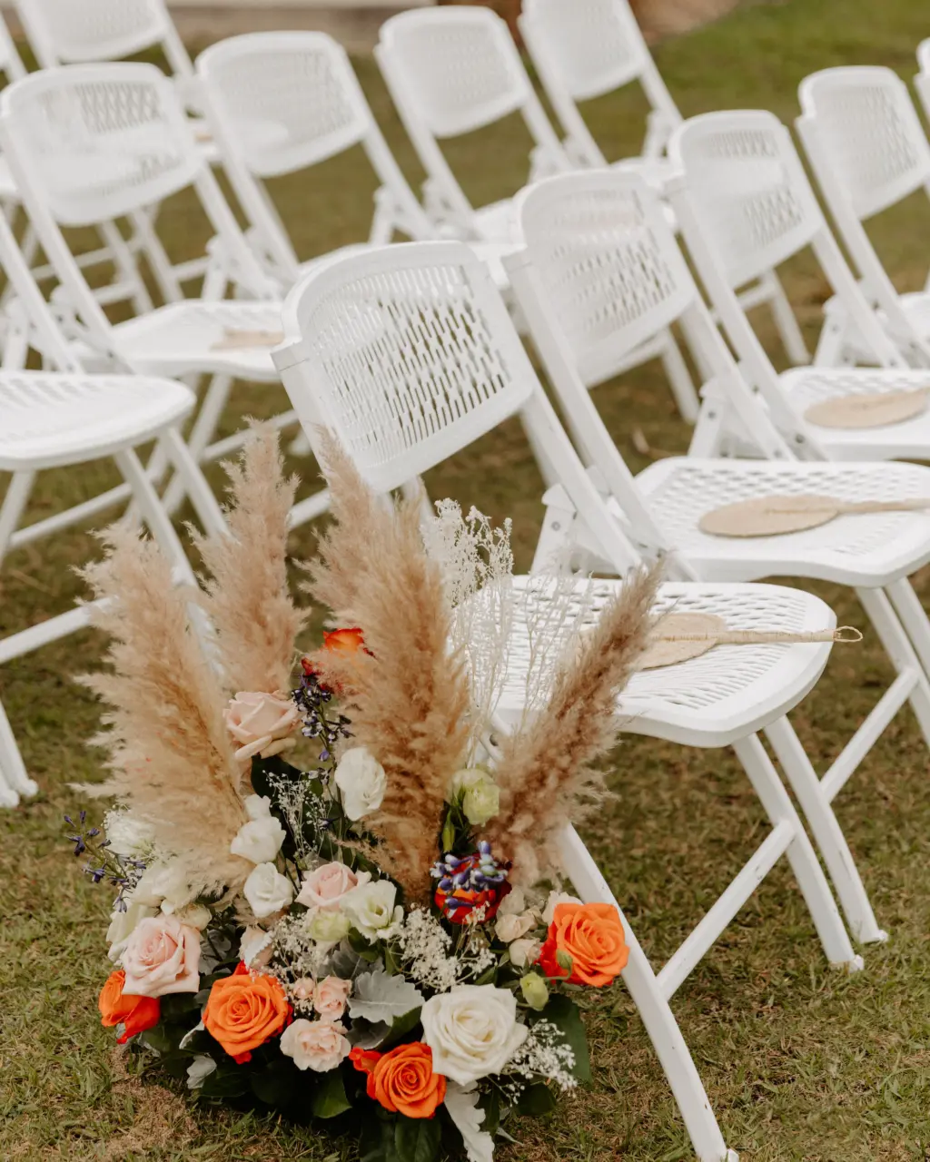 Orange, Pink, and White Roses, Pampas Grass, Baby's Breath, Carnations, and Greenery Boho Floral Aisle Arrangement Ideas | Wedding Guest Fan Inspiration