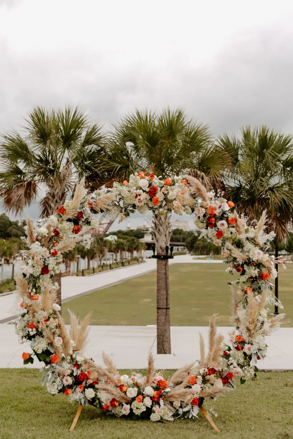 Round Boho Wedding Ceremony Arch Inspiration with Orange and Pink Roses, White Anemones, Pampas Grass, and Greenery