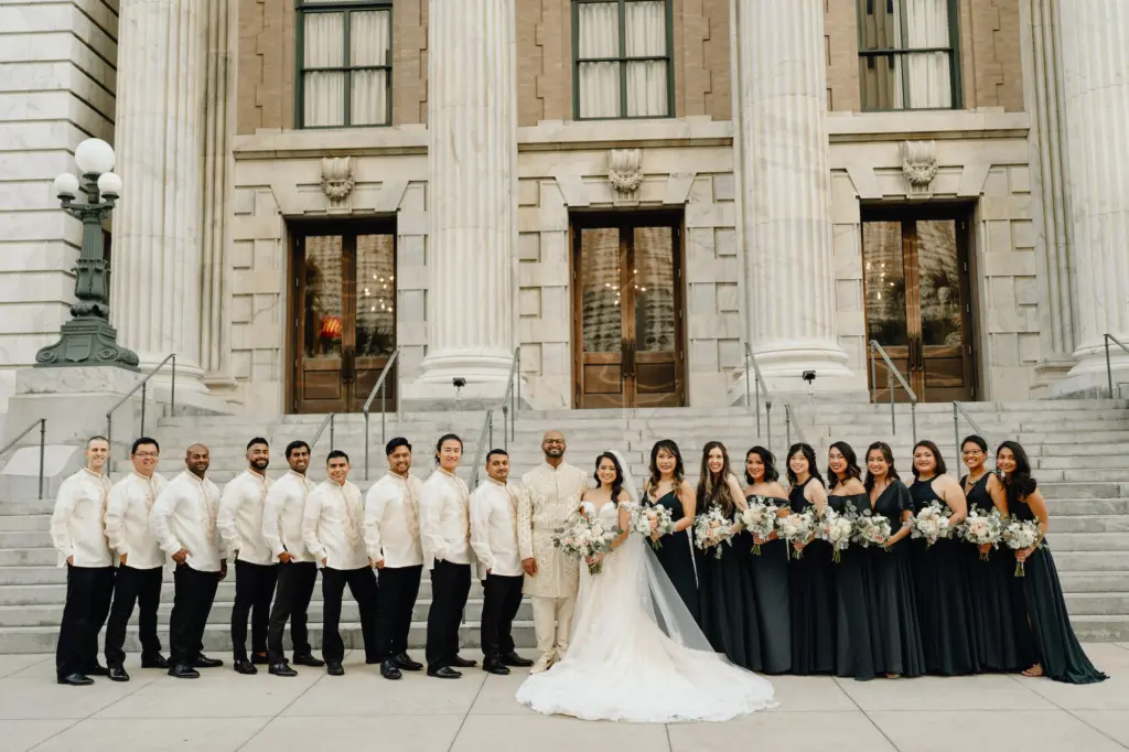 Bridal Party Wedding Portrait | Bridesmaids in Floor Length Mix and Match Bridesmaids Dresses Holding White Floral Bouquets with Eucalyptus | Groomsmen in White and Black Wedding Attire | Downtown Tampa Wedding Venue Le Meridien