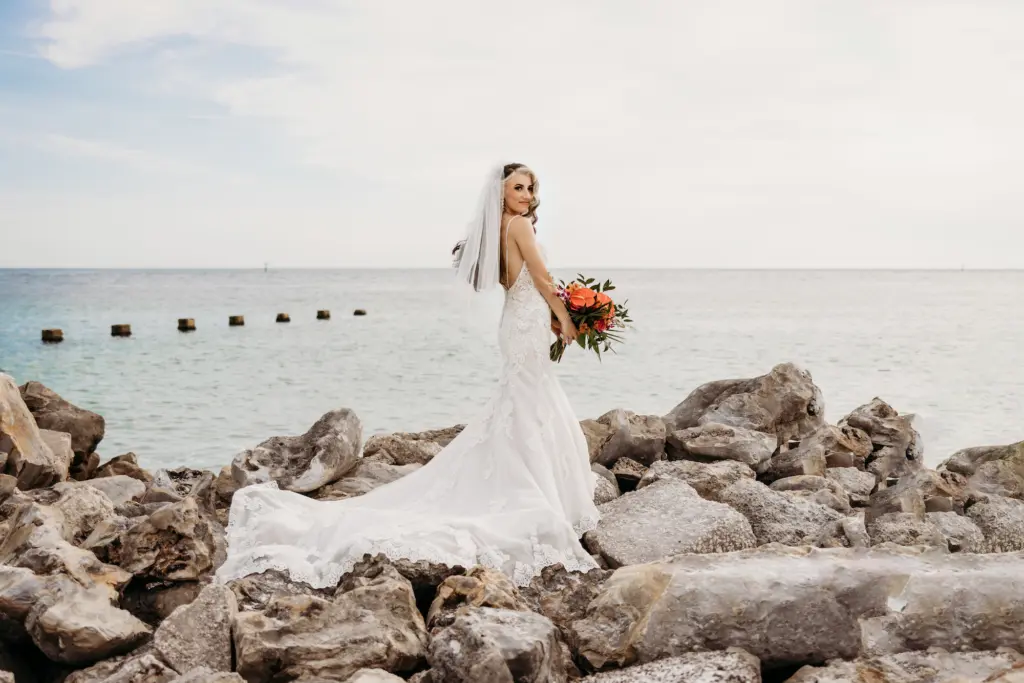 Bridal Wedding Portrait Long Train Wedding Dress with Tropical Wedding Bouquet on Clearwater Beach Rocks | Tampa Wedding Hair and Makeup Adore Bridal