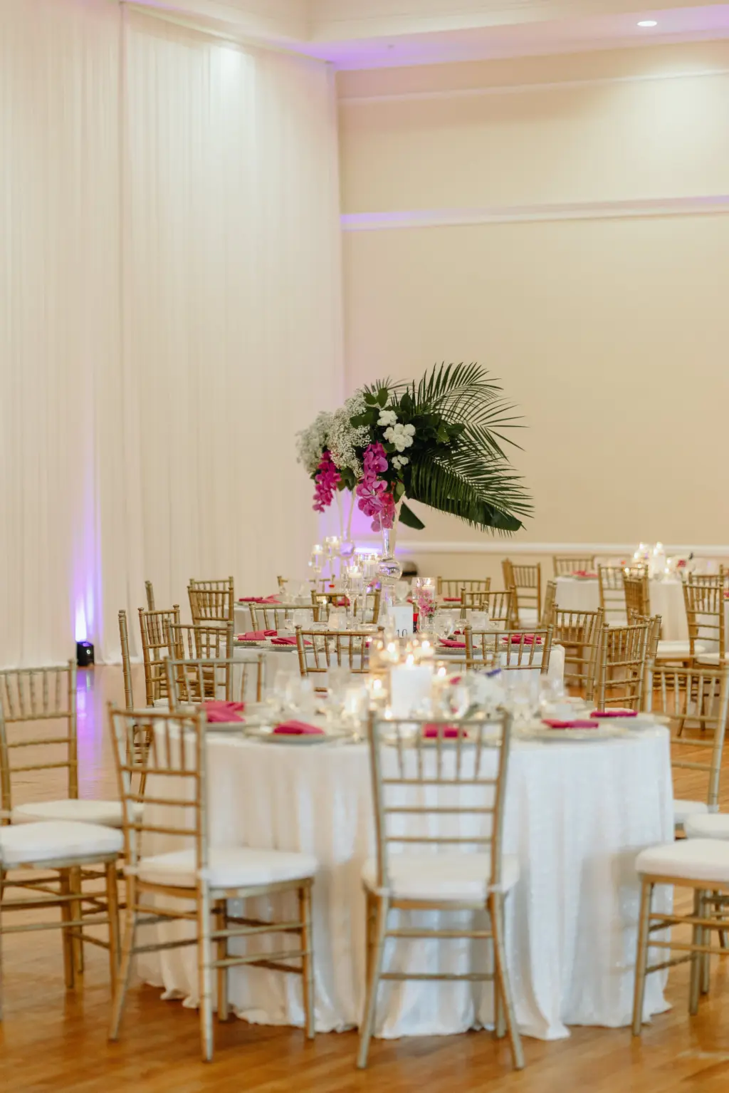 Timeless White Linen Circle Reception Tables with Gold Chiavari Wedding Chairs | Tropical Leave Wedding Centerpiece with Purple Orchids and White Floral Detailing in Asian Fusion Wedding Reception Décor Ideas | Tampa Rental Company A Chair Affair