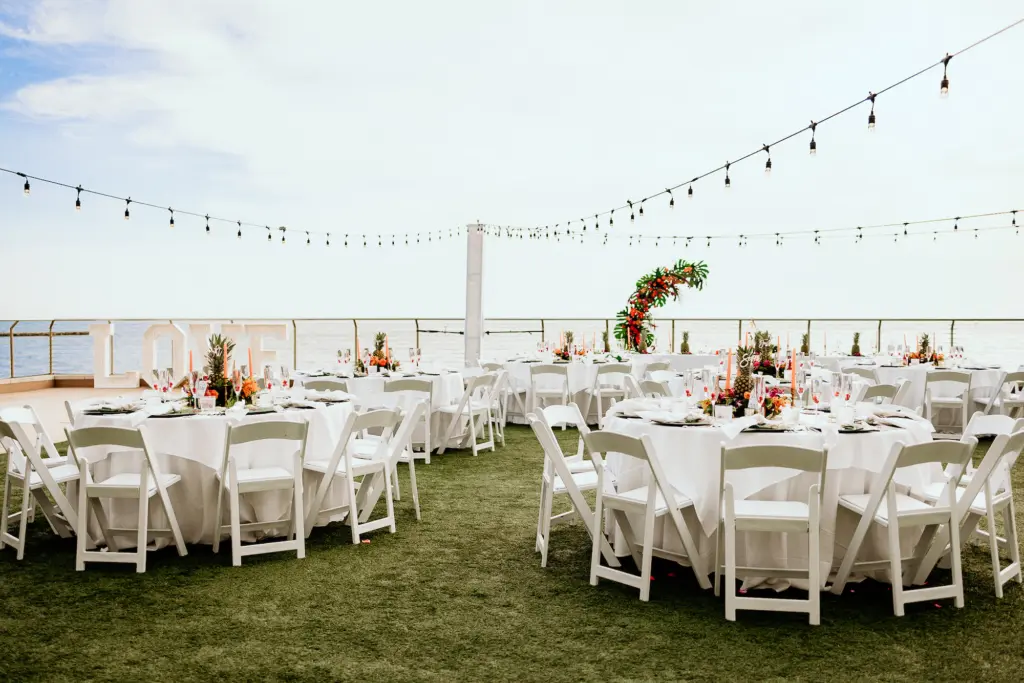 Round Tables with White Linen and White Folding Chair Tropical Outdoor Wedding Reception Inspiration | Clearwater Beach Florist Save the Date Florida | Planner Elegant Affairs by Design | Venue Opal Sands
