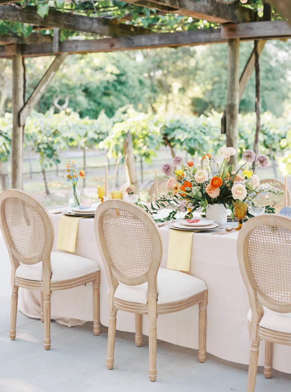White Oak Cane Rattan Spring Wedding Reception Chair Inspiration with Long Feasting Table and Pastel Linen | Fiorella Winery | Colorful Whimsical Wedding Centerpiece Inspiration | Tampa Bay St. Petersburg Florist Save The Date Florida