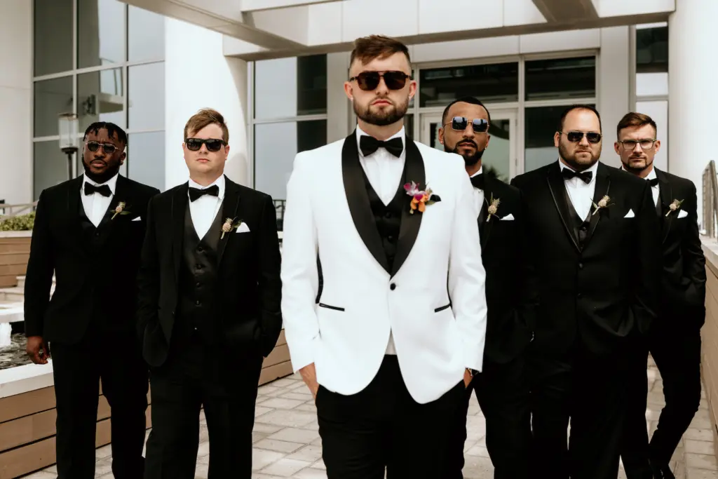Groom in White Tux and Black Bow Tie and Groomsmen in Black Suits Wedding Attire Ideas