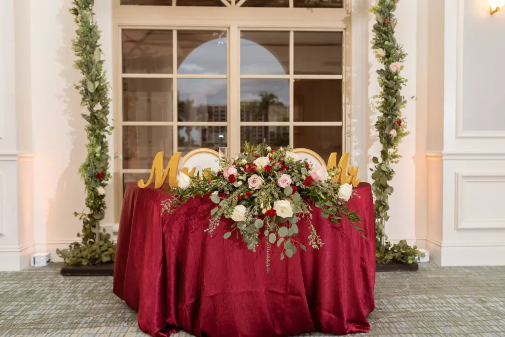 Burgundy and Gold Sweetheart Table | Fall Wedding Reception Decor Inspiration | Pink and White Roses, Burgundy Carnations, and Greenery Table Top Floral Arrangement Ideas | Sarasota Kate Ryan Event Rentals
