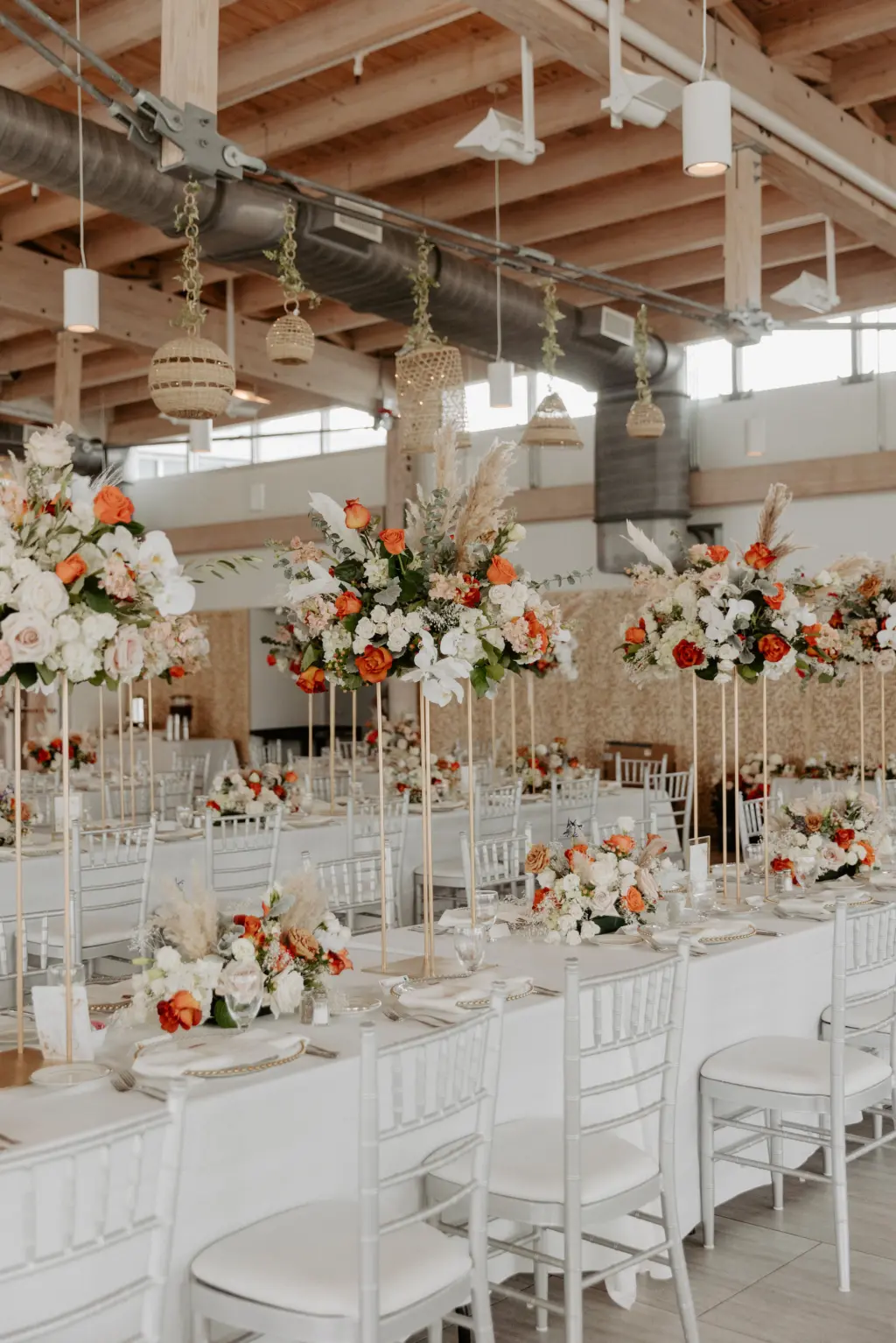 Boho Wedding Reception Inspiration | Silver Chiavari Chairs with White Linen and Long Feasting Tables | Orange, Pink, and White Roses with Greenery Centerpiece Ideas