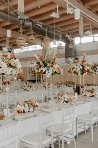 Boho Wedding Reception Inspiration | Silver Chiavari Chairs with White Linen and Long Feasting Tables | Orange, Pink, and White Roses with Greenery Centerpiece Ideas