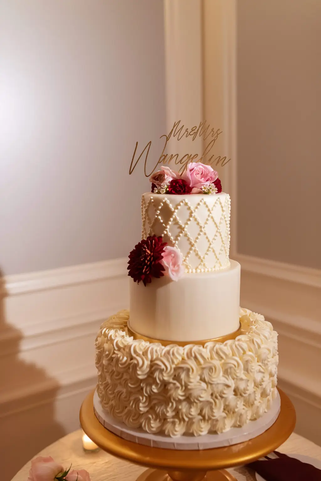 Three-Tiered Round White, Ivory and Gold Textured Wedding Cake With Burgundy Chrysanthemums and Pink Flowers | Gold Last Name Cake Topper