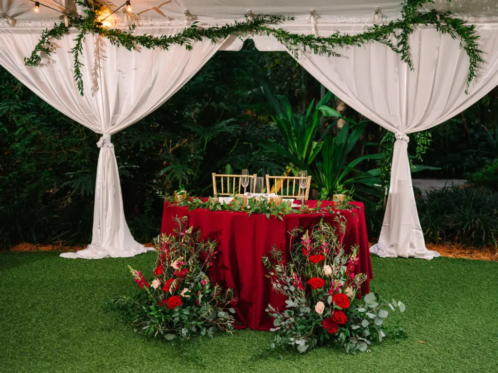 Red and White Christmas Wedding Reception Sweetheart Table Decor Inspiration with Gold Chiavari Chairs | Red Roses and Greenery Floral Arrangements