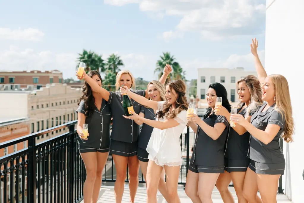 Bride and Bridesmaids Wedding Portrait Popping Champagne on Balcony