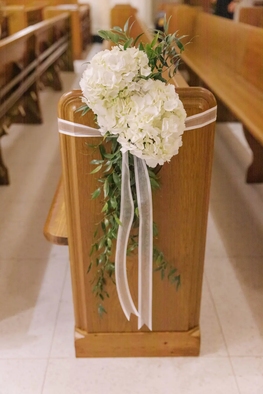 Classic White Hydrangea Details with Greenery and White Ribbon on Church Pews Wedding Ceremony Decor Ideas