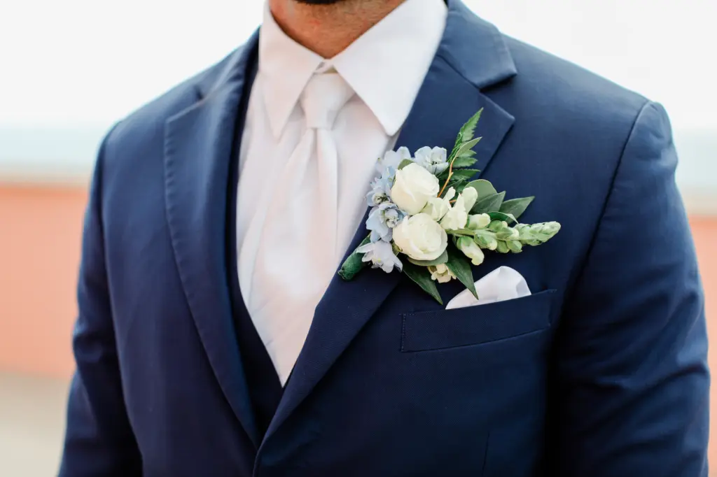 White Spray Roses, Blue Delphinium, and Greenery Wedding Boutonniere Ideas | Three Pieced Navy Wedding Suit with White Tie and Pocket Square Inspiration