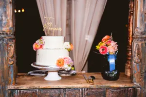 White Round Two-Tiered Wedding Cake with Roses, Pink and Orange Ranunculus Accents