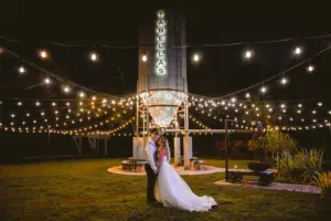Bride and Groom Under Marget Lights and Silo Wedding Portrait | Tampa Bay Planner B Eventful | Event Venue Tabellas at Delaney Creek