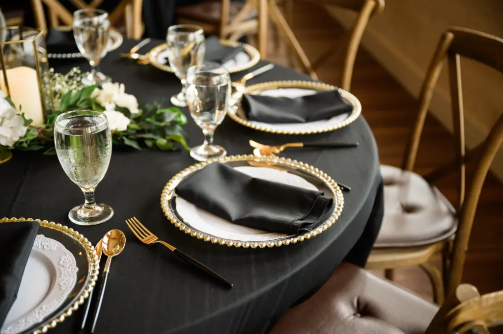 Elegant Southern Wedding Reception Table Setting Inspiration with Black and Gold Flatware, Black Linen, and Beaded Chargers