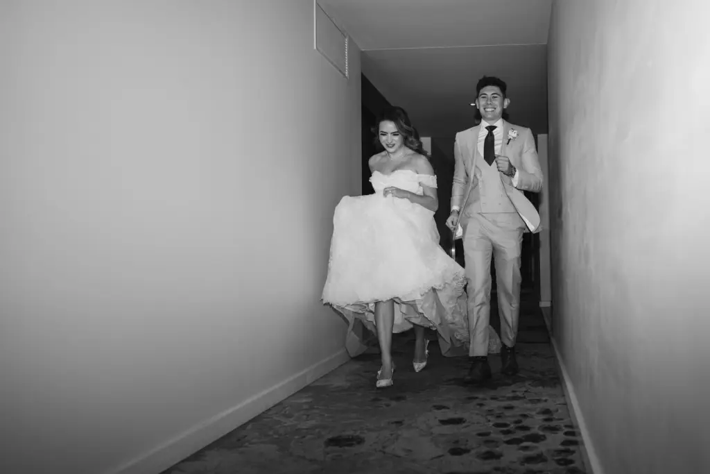 Bride and Groom Running Down Hallway After Wedding