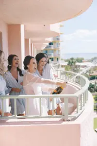 Bride and Bridesmaids Popping Champagne on Balcony on Wedding Day