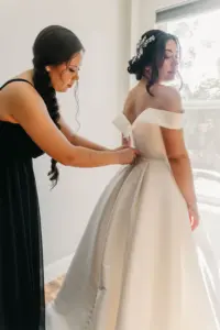 Bride and Bridesmaid Getting Ready | Off-The-Shoulder Satin A-Line Ballgown Essence of Australia Wedding Dress with Crystal Belt Inspiration