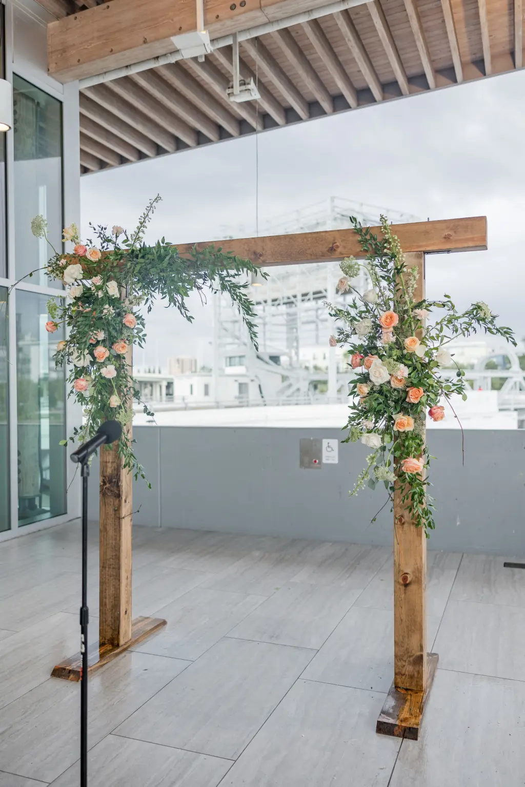 Rustic Wooden Arch with Pink, Orange, and White Roses and Greenery for Downtown Tampa Outdoor Rooftop Garden Wedding Ceremony Decor Ideas