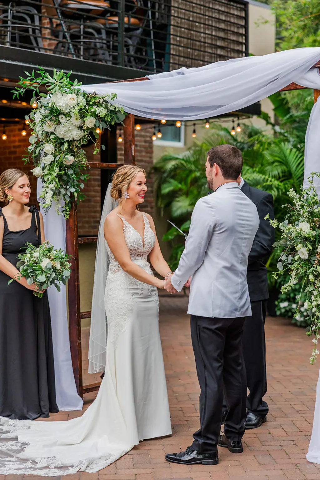 Bride and Groom Vow Exchange | White Drapery with White Hydrangeas, Roses, Veronicas, and Greenery Wedding Ceremony Arch Decor Inspiration | Tampa Bay Rental Company A Chair Affair