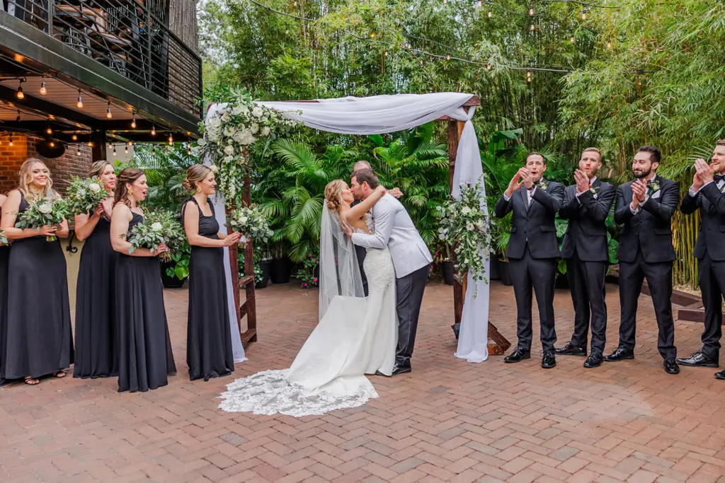 Bride and Groom First Kiss Wedding Portrait | White Drapery with White Hydrangeas, Roses, Veronicas, and Greenery Wedding Ceremony Arch Decor Inspiration | Tampa Bay Event Venue Nova 535 | St Pete Photographer Eddy Almaguer Photography | Arch Rental A Chair Affair