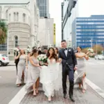 Wedding Party Walking Down Road in Downtown Tampa Inspiration | Black Tuxedo Suits and Neutral Cream Satin Bridesmaids Dresses | Tampa Bay Wedding Videographer J&S Media