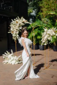 Gold Metal Hoop Arch with White Monochromatic Floral Arrangement for Modern Great Gatsby Inspired Wedding Ceremony | One-Shoulder White Fit and Flare Wedding Dress with Feathers and Thigh Slit | St Pete Boutique Truly Forever Bridal