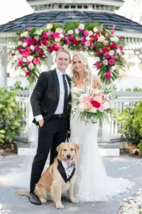Bride and Groom with Dog Wearing Wedding Tuxedo Bandana | Tropical Pink and White Wedding Ceremony Gazebo Altar Decor Inspiration
