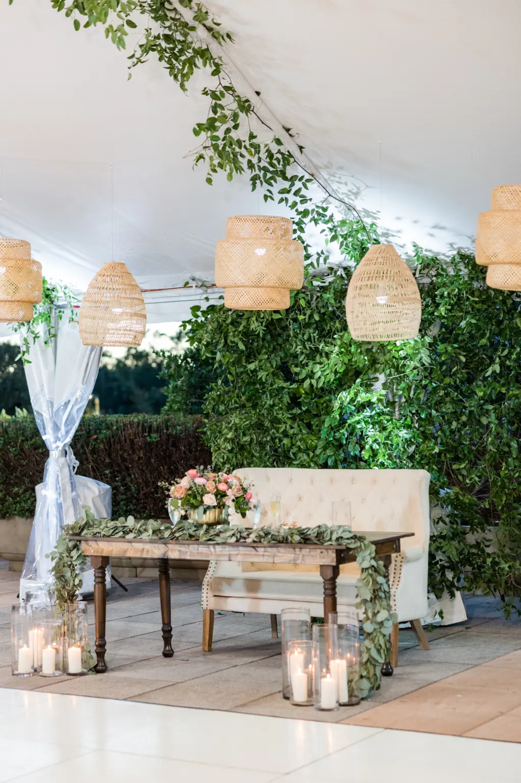 Wedding Reception Sweetheart Table with Tufted Loveseat, Wooden Farm Table, Greenery Garland, Boho Chandeliers, and Floor Candle Decor Inspiration | Tampa Bay Kate Ryan Event Rentals
