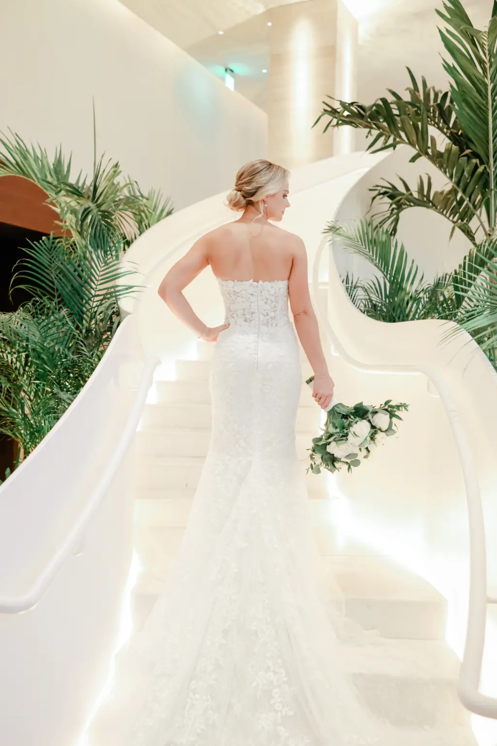 Elegant Wedding Hair and Makeup Inspiration | Low Bridal Bun Chignon Ideas | Strapless White Floral Applique Pronovias Mermaid Wedding Dress with Cathedral Length Train | Downtown Event Venue The Edition Hotel Tampa Water Street Lobby Staircase | Bridal Portrait Inspiration