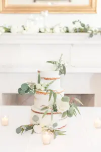 Three-Tiered Semi Naked Ivory Buttercream Wedding Cake with Greenery Accents
