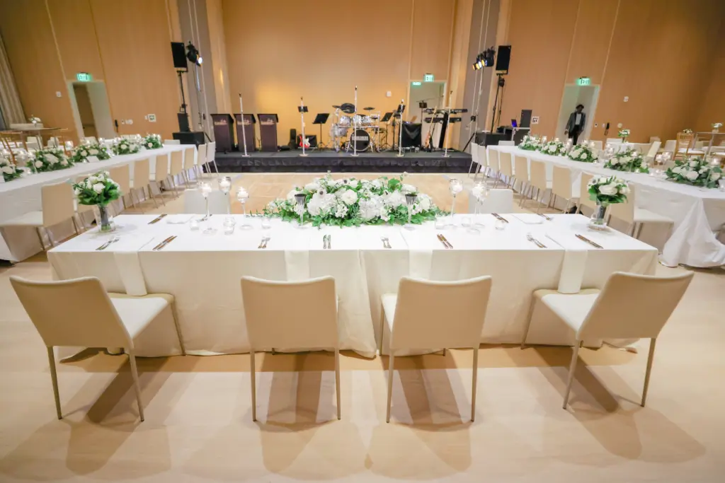Timeless Monochromatic White Wedding Reception Head Table Decor Ideas | White Roses, Hydrangeas, Anemones, and Greenery Centerpiece Inspiration | Modern Cream Chairs | Tampa Bay Planner Breezin' Weddings | Downtown Event Venue The Edition Hotel Tampa Water Street Ballroom