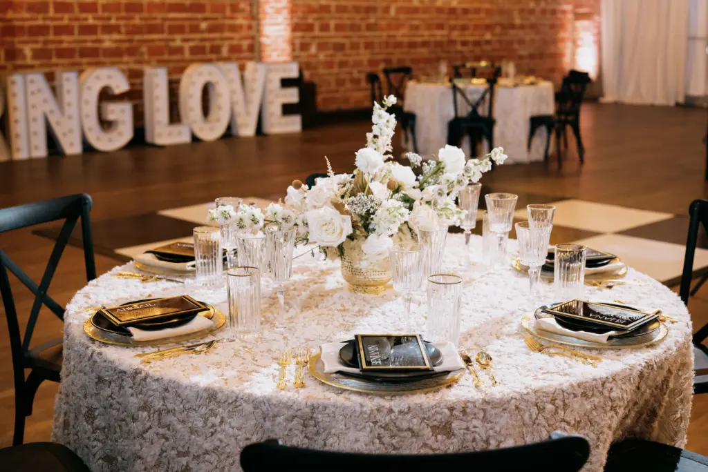 White Roses, Stock Flowers, and Hydrangeas Centerpiece Inspiration | Black and Gold Table Setting Ideas for Modern Great Gatsby Themed Wedding Reception Ideas | St Pete Kate Ryan Event Rentals | Florist Marigold Flower Co