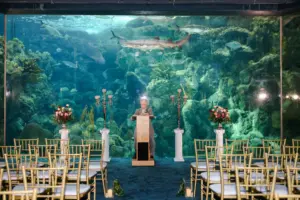 Blue, Pink, and Gold Coral Reef Gallery Wedding Ceremony Decor Ideas | Tampa Bay Event Venue The Florida Aquarium | Gold Chiavari Chairs and Gold Candelabras on White Columns Decor Ideas | Tampa Bay Gabro Event Rentals