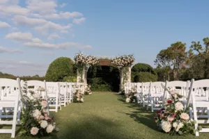 Luxurious Outdoor Wedding Ceremony on the Event Lawn Inspiration | White and Pink Roses, Hydrangeas, Chrysanthemums, and Greenery Aisle Decor Ideas | White Folding Garden Chairs | Tampa Bay Venue The Concession Golf Club | Planner Parties A La Carte | Florist Bruce Wayne Florals