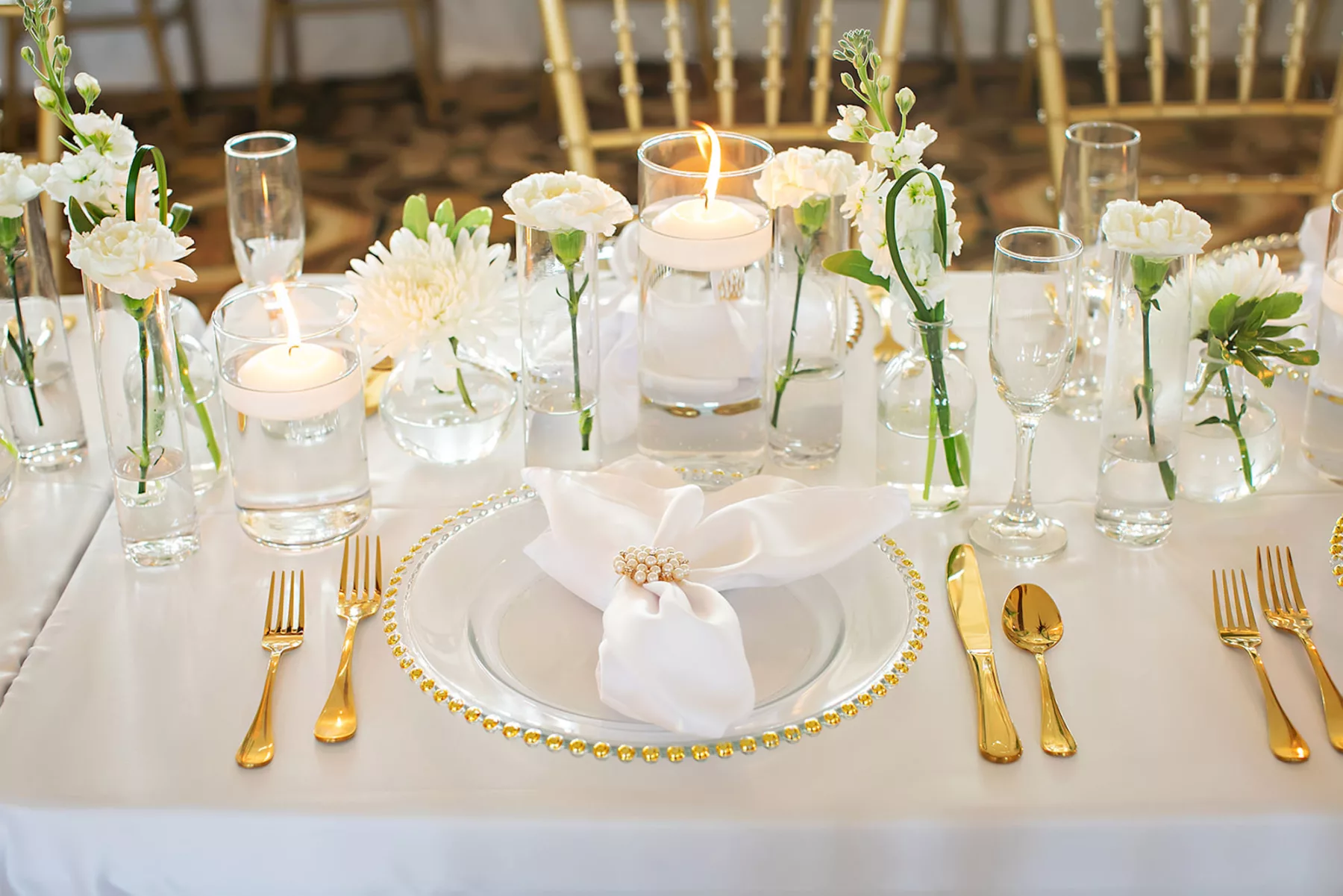 White Monochromatic Wedding Reception Centerpiece Decor Inspiration | Gold Rimmed Beaded Chargers, Gold Flatware | Floating Candles, White Carnations and Chrysanthemums in Tall Glass Bud Vase Flower Arrangement Ideas | Tampa Planner Coastal Coordinating | Outside the Box Event Rentals