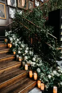 Flameless Candles with Cascading Lush Greenery on Stairs with White Veronica, Roses, Hydrangeas, and Eucalyptus | Romantic Black and White Wedding Reception Decor Ideas | Tampa Bay Event Venue Oxford Exchange | Planner Wilder Mind Events