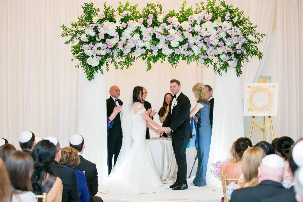 Elegant Jewish Wedding Ceremony Inspiration | Chuppah with Drapery, Pink and Purple Roses, White Hydrangeas, and Greenery Inspiration