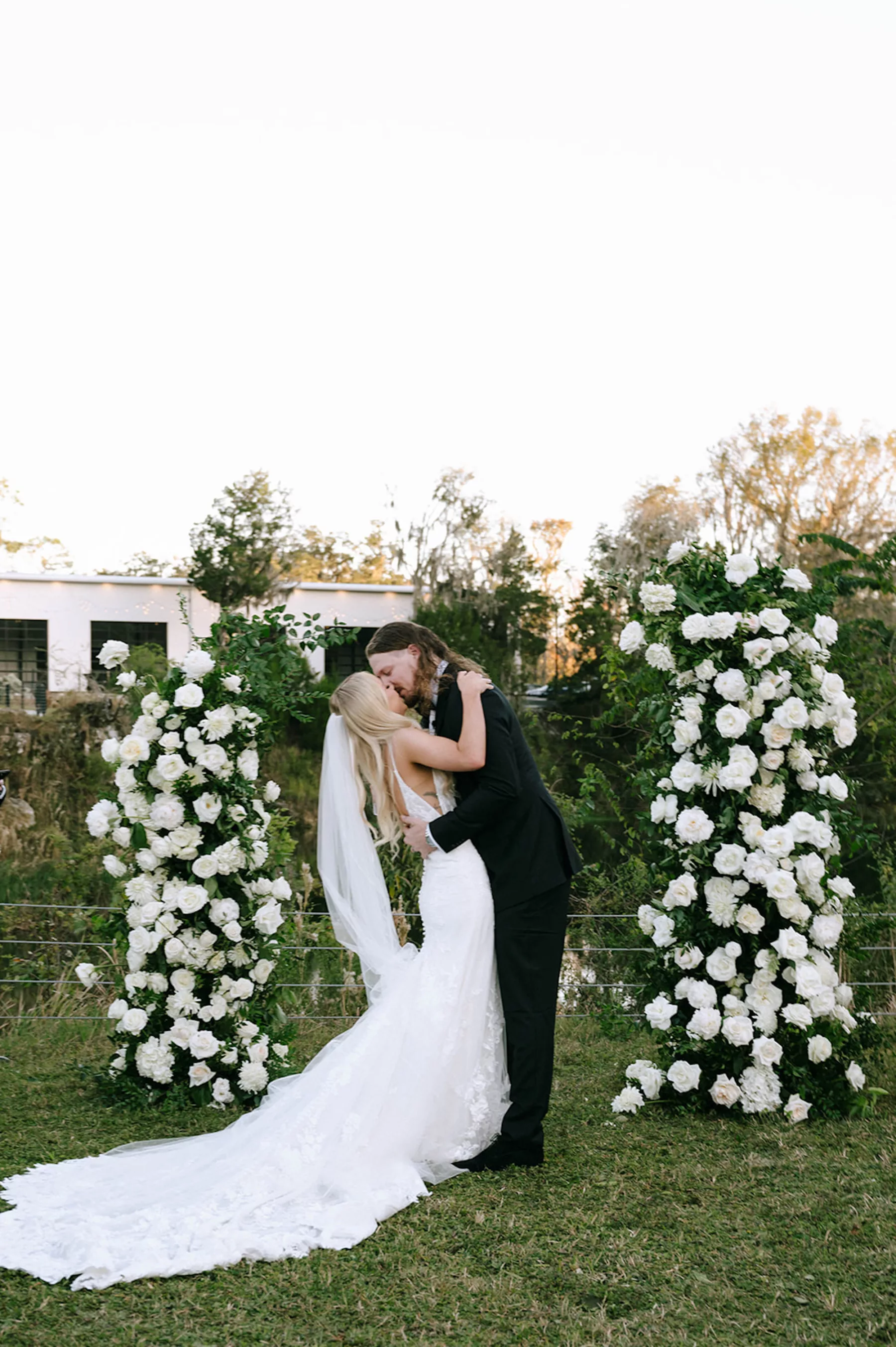 Bride and Groom First Kiss Wedding Portrait | Asymmetrical Floral Arbor with White Roses and Greenery Ideas | Tampa Bay Florist Bloom Shakalaka | Planner Kelci Leigh Events